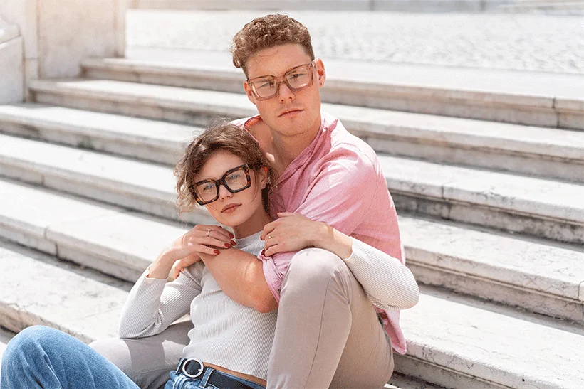 Couple wearing modern tortoise shell and transparent designer glasses while sitting on stone steps